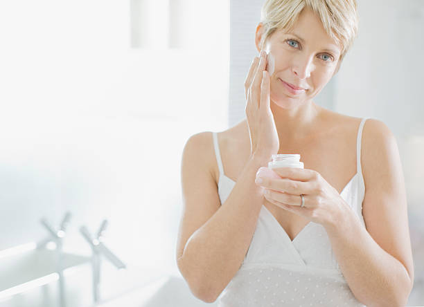 woman applying face cream in the morning - smörja in sig bildbanksfoton och bilder