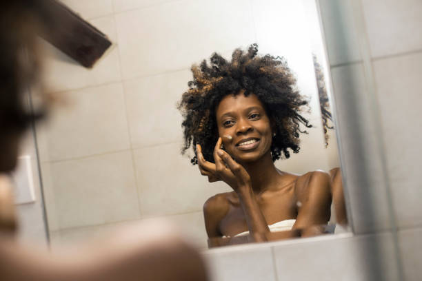 Woman applying face cream Young woman in her bathroom, appplying face cream. About 25 years old, African female. applying face cream stock pictures, royalty-free photos & images