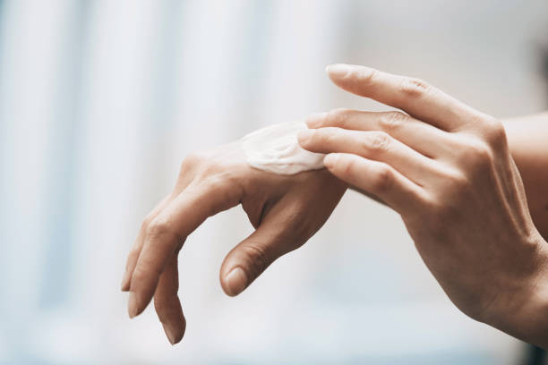 Woman applying moisturizing cream on hands stock photo