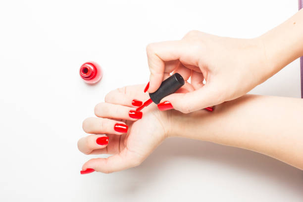 Woman applying red nail polish her nails manicure on white Manicure - Beautiful manicured woman's nails with red nail polish on white background painting fingernails stock pictures, royalty-free photos & images