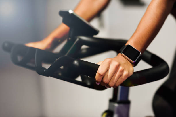Woman at a gym doing exercising or cyclo indoor with smart watch Hands of a woman training at a gym doing exercising or cyclo indoor with smart watch. Sports and fitness concept. spinning stock pictures, royalty-free photos & images