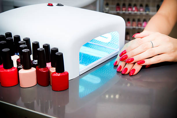 A woman at a nail salon drying her nails Manicure set in a beauty salon. Beautiful female hands. Machine for drying naroshchennyh nail UV lamp. artificial nail stock pictures, royalty-free photos & images