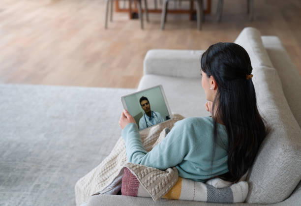 Woman at home feeling poorly and talking to her doctor on a video call stock photo
