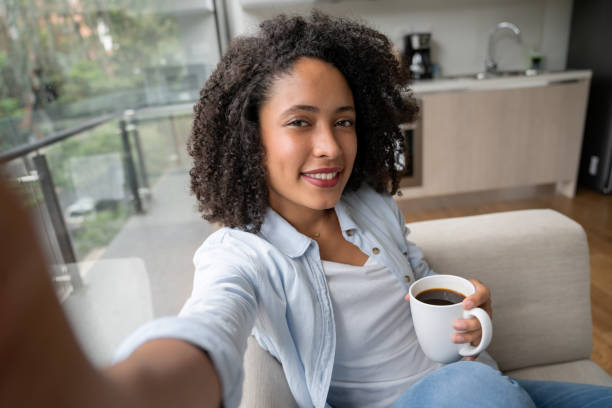 mujer en casa tomando un selfie mientras bebe café - autofoto fotografías e imágenes de stock