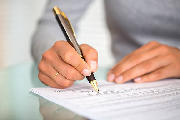 Woman at office desk signing a contract stock photo
