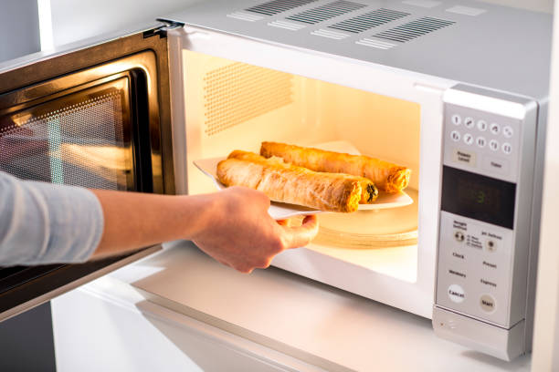 A woman Baking Pastry In Microwave Oven stock photo
