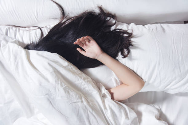 woman black hair sleeping on white color pillow and the bed stock photo