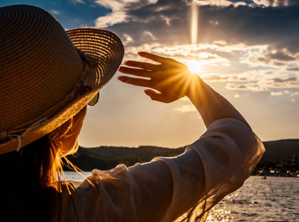 Woman blocking sun with hands stock photo