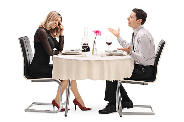 Woman breaking up with her boyfriend Young woman breaking up with her boyfriend seated at a restaurant table isolated on white background bad date stock pictures, royalty-free photos & images