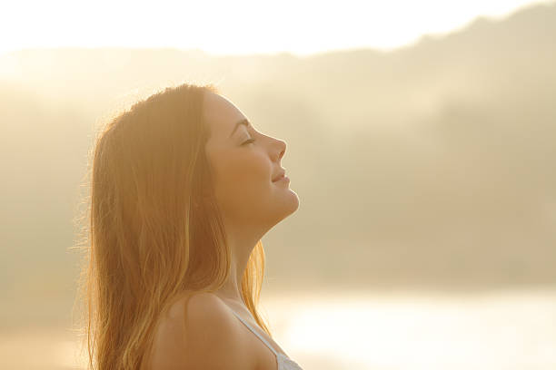 Woman breathing deep fresh air in the morning sunrise Backlight profile of a woman breathing deep fresh air in the morning sunrise isolated in white above image technique stock pictures, royalty-free photos & images