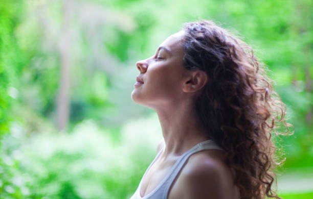 Woman breathing fresh air outdoors in summer Young woman enjoying yoga, relaxing, feeling alive, breathing fresh air, calm and dreaming with closed eyes, in public park inhaling stock pictures, royalty-free photos & images