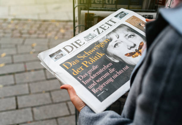 Woman buying German Die Zeit newspaper with Angela Merkel Strasbourg: Woman reading buying German Die Zeit newspaper at press kiosk featuring Angela Merkel and tilte The Silenece of Politics chancellor stock pictures, royalty-free photos & images