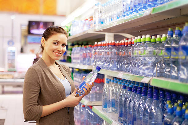 woman buys a water bottle in shop - soda supermarket stockfoto's en -beelden