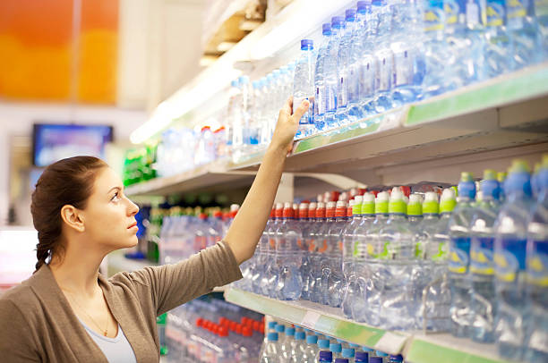 woman buys a water bottle in shop - soda supermarket stockfoto's en -beelden