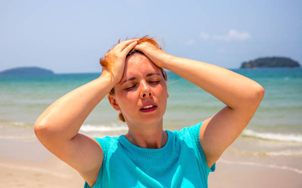 Woman by seaside with sunstroke. Health problem on vacation. Medicine on vacation. stock photo