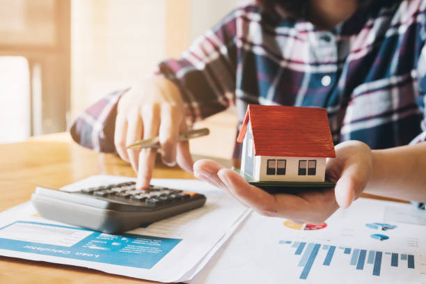 집 모델 홈에서 테이블에서 부동산 프로젝트 계약을 서명 하기 전에 예산을 계산 하는 여자 - mortgage 뉴스 사진 이미지