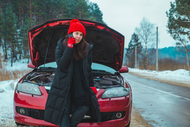 woman calling for help with broken down car at winter highway stock photo