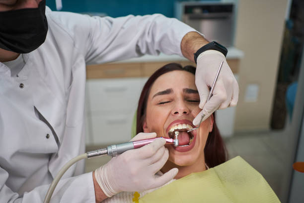 Woman can’t hide her fear while the male dentist repairing some tooth decay stock photo