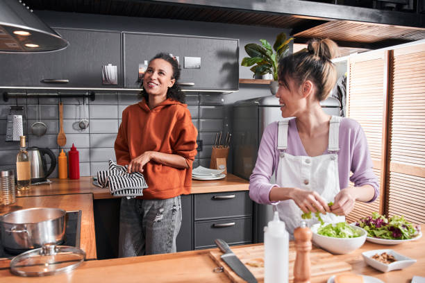Woman chatting with bestie while preparing salad at table stock photo