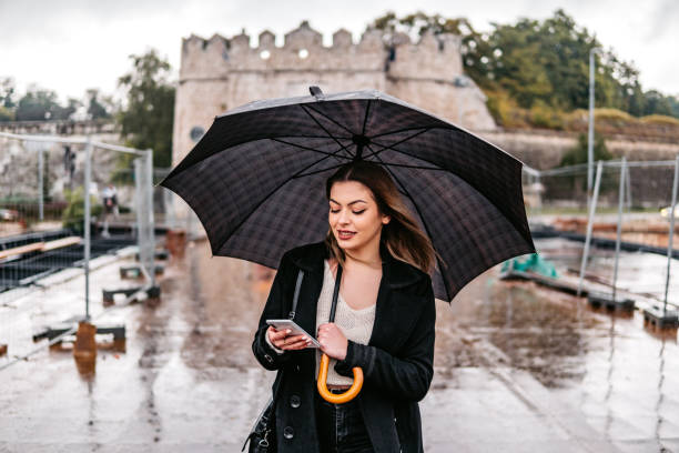 Woman checking social media in rain  an umbrella stock pictures, royalty-free photos & images