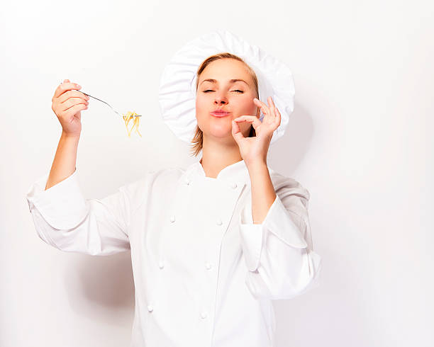 Woman chef showing a sign perfect, with pasta noodle. stock photo
