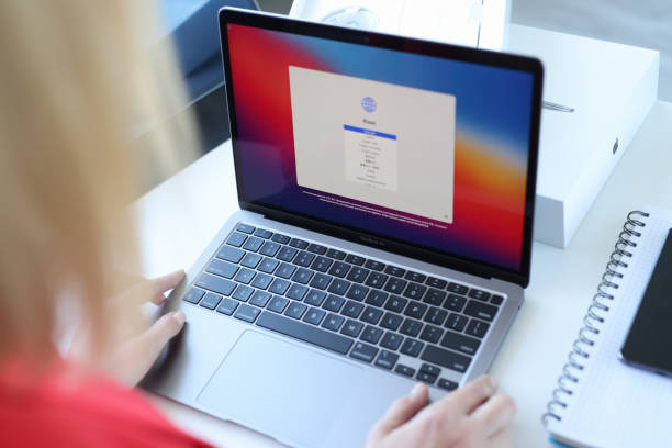 Woman choosing language on new laptop Apple MacBook air closeup stock photo