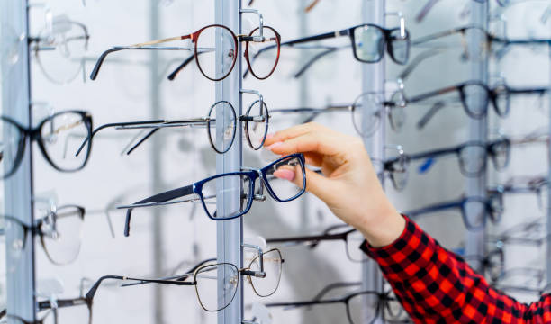 Woman choosing new pair of spectacles in opticians store. stock photo