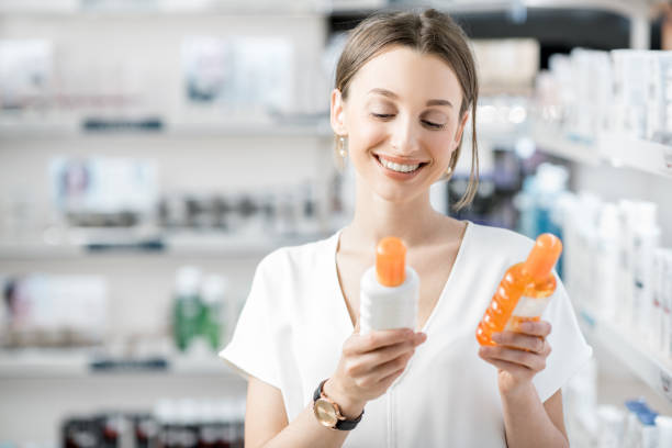 Woman choosing sunscreen lotion at the pharmacy Young woman customer choosing sunscreen lotion at the pharmacy store sunscreen stock pictures, royalty-free photos & images