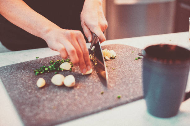 Woman chopping fresh garlic and green chili stock photo
