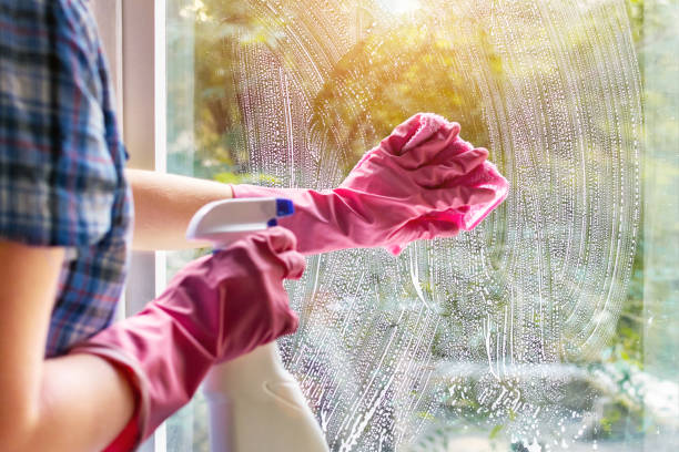 A woman clean a window pane with a rag and soap suds. Cleaning with a detergent. Hands in pink protective gloves washing glass on the windows of the house with a spray bottle, home routine. A woman clean a window pane with a rag and soap suds. Cleaning with a detergent. Hands in pink protective gloves washing glass on the windows of the house with a spray bottle, home routine concept. window cleaning stock pictures, royalty-free photos & images