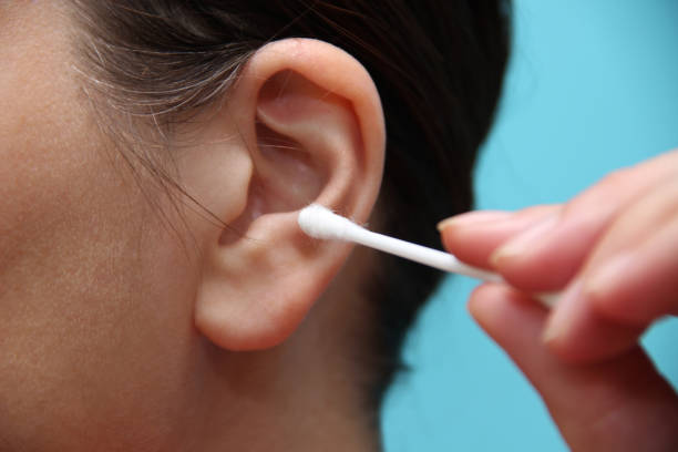 Woman cleaning ear with cotton swab stock photo