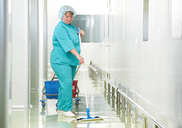 Woman cleaning hospital hall Adult cleaner maid woman with mop and uniform cleaning corridor pass floor of pharmacy industry factory or clinic cleaner stock pictures, royalty-free photos & images