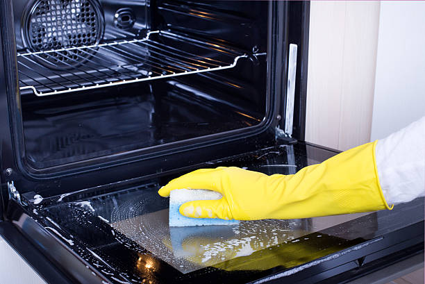 Woman cleaning oven Close up of female hand with yellow protective gloves cleaning oven door oven stock pictures, royalty-free photos & images