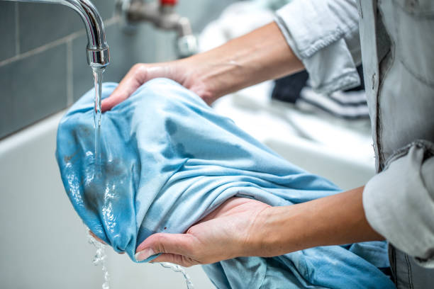 Woman Cleaning Stained Shirt in Bathroom Sink Woman Cleaning Stained Shirt in Bathroom Sink. stained stock pictures, royalty-free photos & images