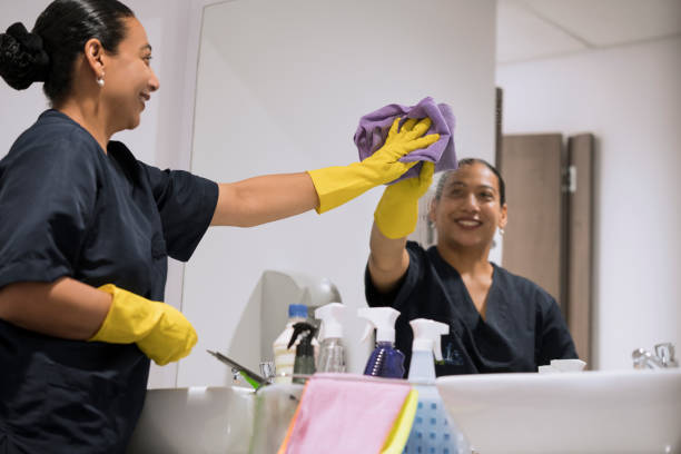 Woman cleaning the bathroom mirror Latin woman between 35 - 45 years old is smiling cleaning the bathroom mirror office cleaning stock pictures, royalty-free photos & images
