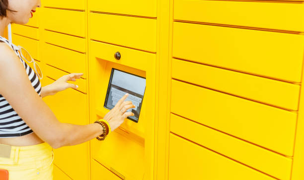 Woman client using automated self service post terminal machine or locker to deposit the parcel for storage, Woman client using automated self service post terminal machine or locker to deposit the parcel for storage, self service photos stock pictures, royalty-free photos & images