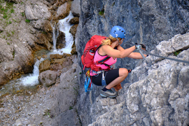 Woman climber at Hanauer via ferrata route in Tirol, Austria, near a water stream. stock photo