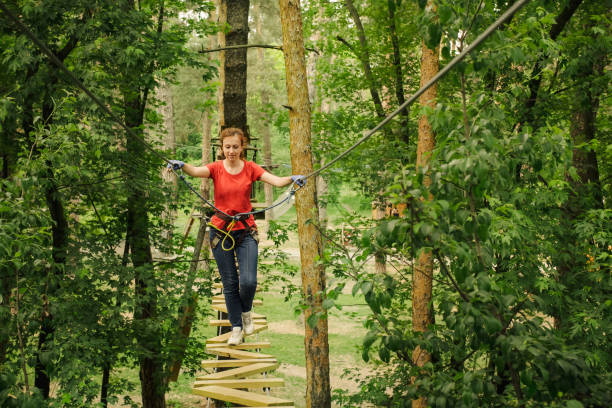 Woman climbing in forest adventure rope park stock photo