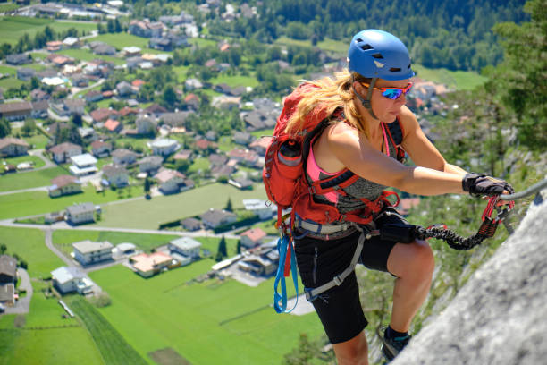 Woman climbs via ferrata route Nassereith above Dormitz village, Austria. Summer, adventure, tourism. stock photo