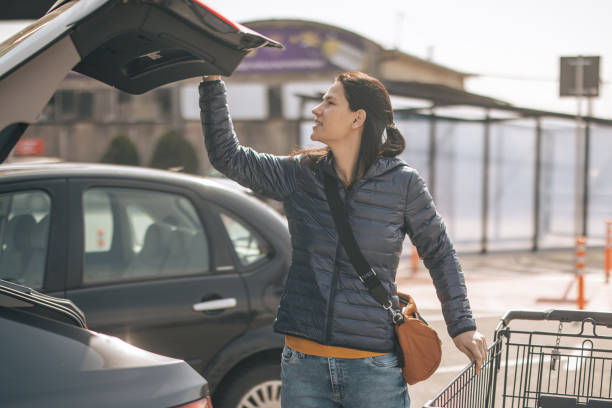woman closing car trunk after shopping - fechar porta bagagens imagens e fotografias de stock