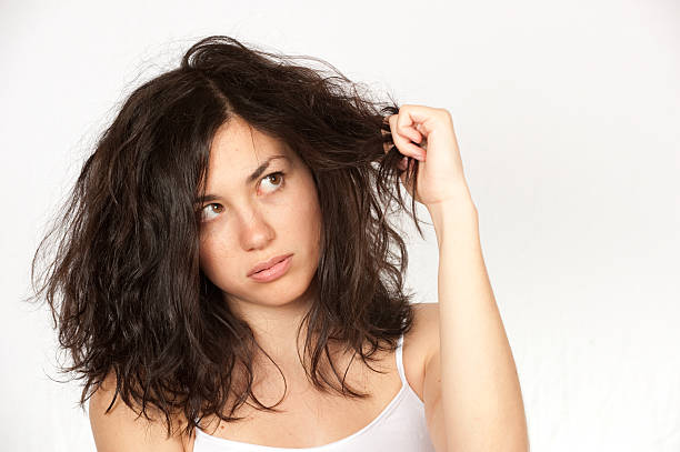 Woman clutching wavy dark hair over a white background A woman looking at her bad hair. human hair stock pictures, royalty-free photos & images