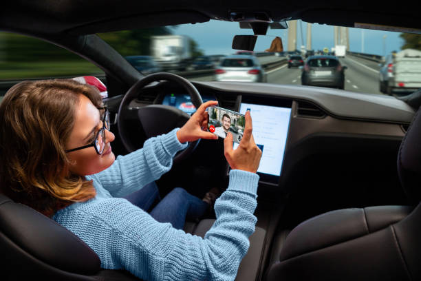 frau kommuniziert per videoanruf, während ihr auto von einem autopilot gefahren wird - fahrerloses auto stock-fotos und bilder
