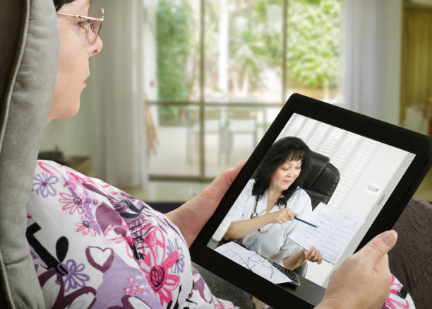 Woman communicates with telemedicine doctor by digital tablet stock photo