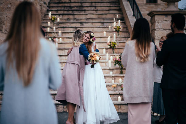 Woman congratulating bride at rustic cottage wedding reception Loving mother embracing elegant bride at outdoors rustic cottage wedding ceremony in Europe mother of the bride dress stock pictures, royalty-free photos & images