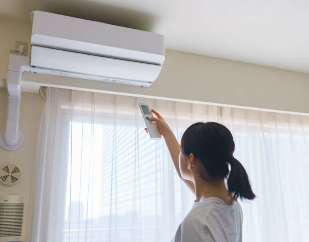 日本のリビングルームでエアコンの電源をオンにする女性コントロール - エアコン　部屋 ストックフォトと画像