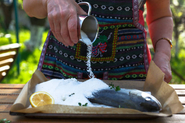 A woman cook a fish in a salt crust. stock photo