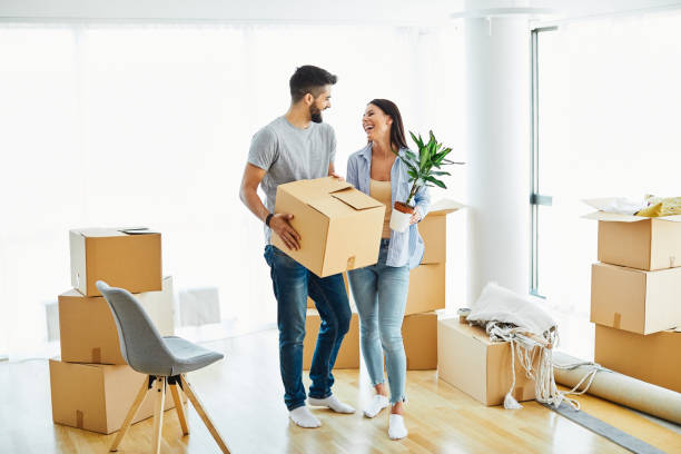 woman couple man box home house moving happy apartment together romantic relocation new property Portrait of a lovely young couple moving in a new house unpacking stock pictures, royalty-free photos & images