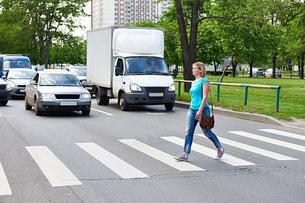 Woman crossing the street at pedestrian crossing stock photo