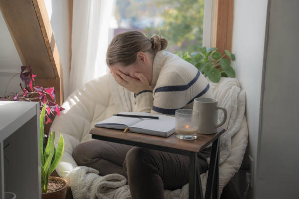 Woman Crying at home with an open Journal stock photo