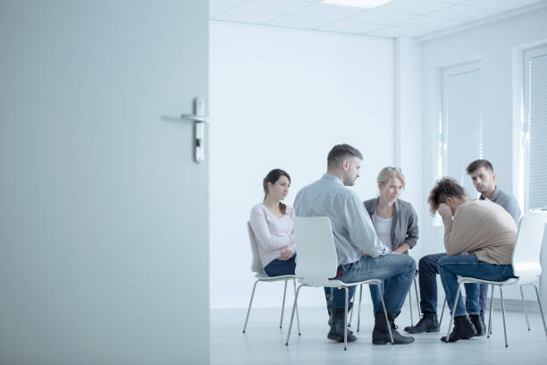 Woman crying in rehab center Woman crying while sitting in circle during meeting with support group in rehab center drug rehab stock pictures, royalty-free photos & images